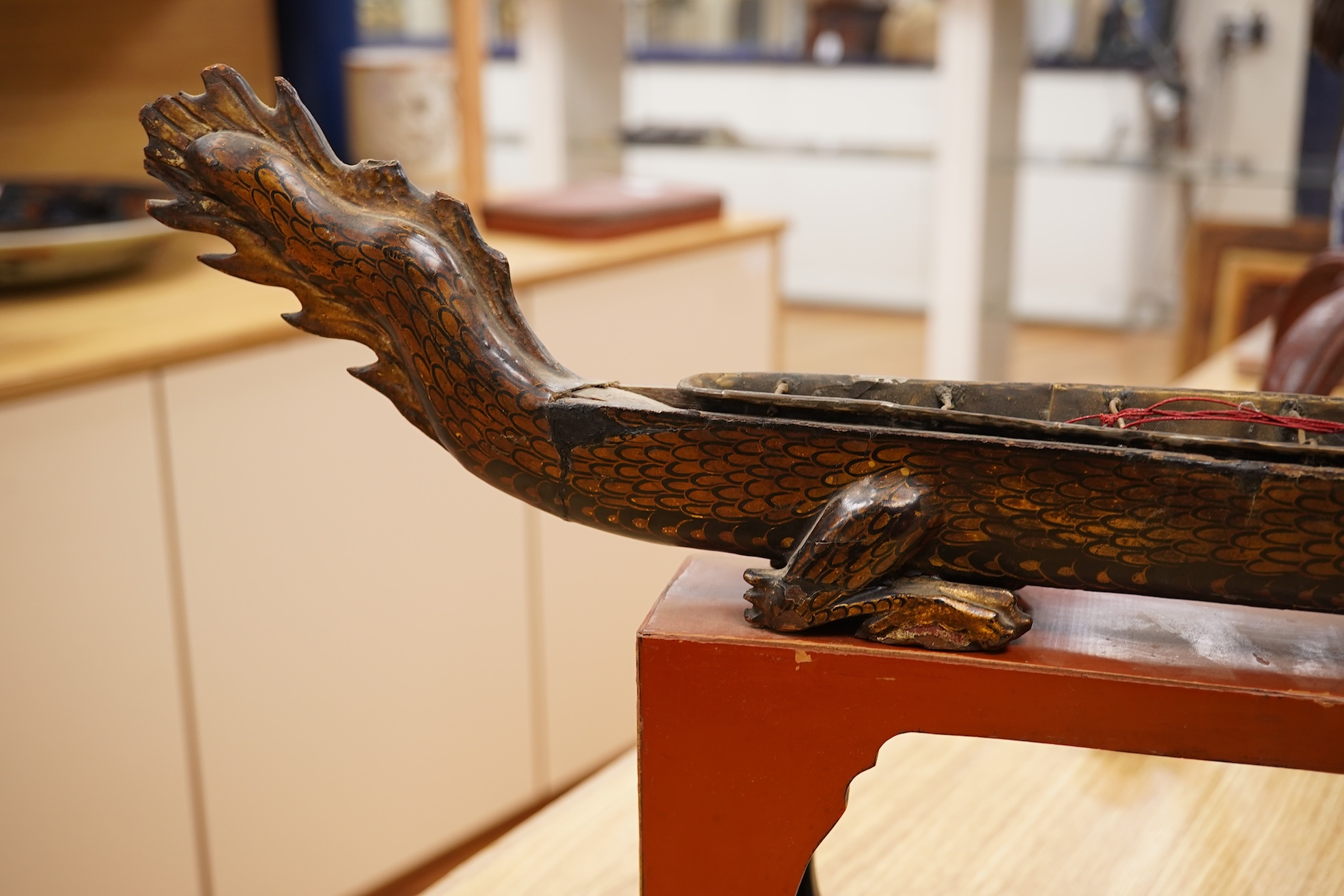 A South East Asian gilt decorated black lacquer model 'dragon' boat on stand, 75cm